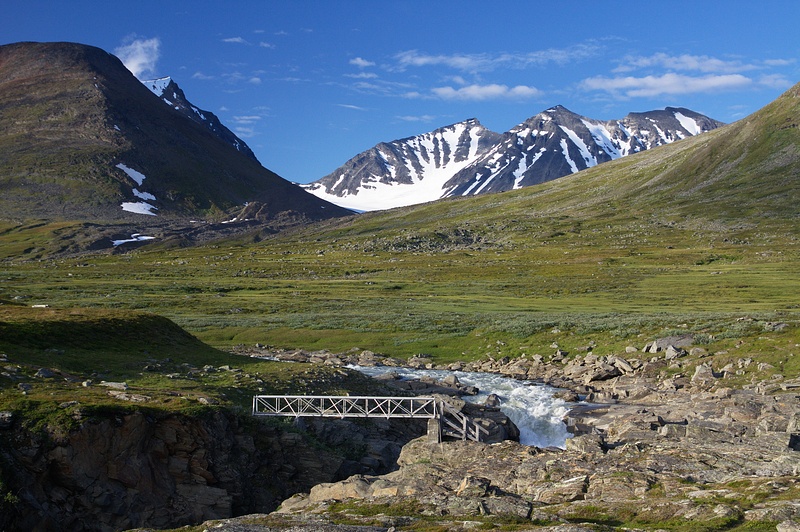 IMG_8005.jpg - Skárjá - most přes ledovcovou řeku Smájllájåhkå. Nejvyšší vrcholy Sareku se tyčí v pozadí - Sarektjåhkkå, Stortoppen (2089 m) vlevo a Sydtoppen (2023 m) uprostřed